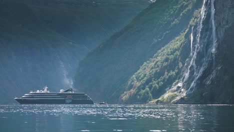 a cruise ship approaches the seven sisters waterfall, set against the stunning cliffs of geiranger fjord