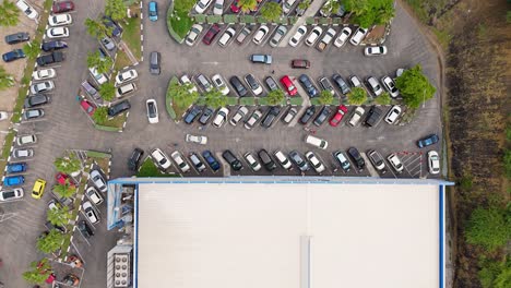 vista estática aérea de arriba hacia abajo de los coches dando vueltas en el estacionamiento de la tienda de supermercado