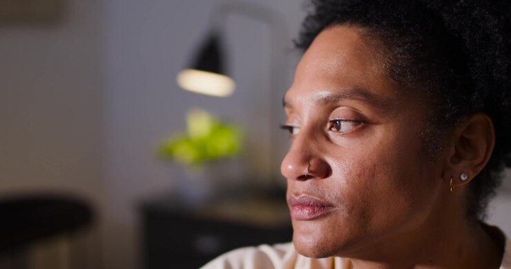 Adult African American woman sitting home thinking, nose ring or hoop tracking gaze down up under la