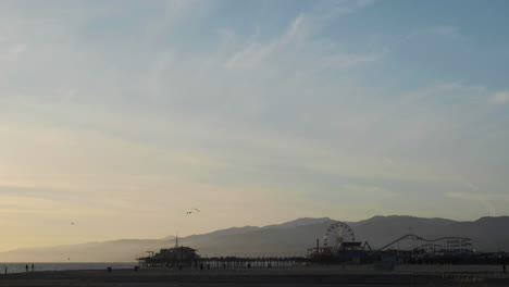 Santa-Monica-Pier-Bei-Sonnenuntergang-Mit-Fliegenden-Vögeln-In-Zeitlupe