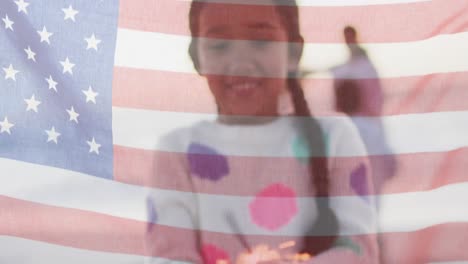 Animation-of-flag-of-united-states-of-america-over-biracial-girl-holding-cupcake-by-seaside