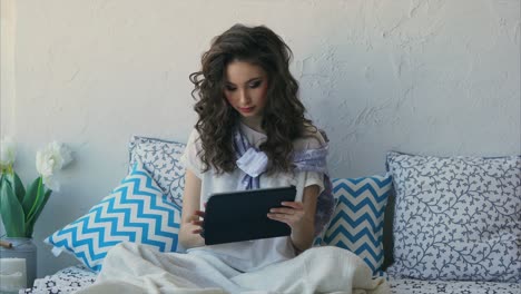 mujer relajándose en la cama con la tableta