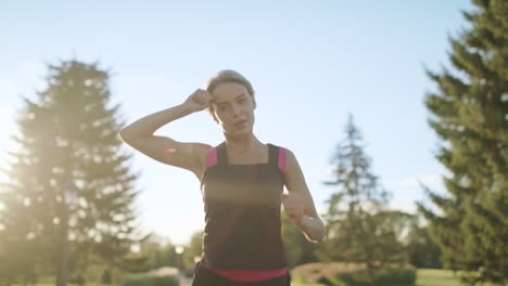 Mujer-Corriendo-Secándose-El-Sudor-De-La-Frente-Por-La-Mañana-Trotando-En-El-Parque