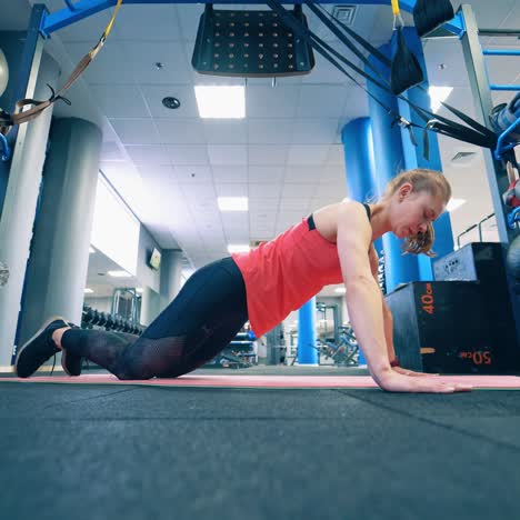 young sportswoman doing push-ups on a mat. side view of a girl training on the floor in the gym. active female in sportswear doing workout.