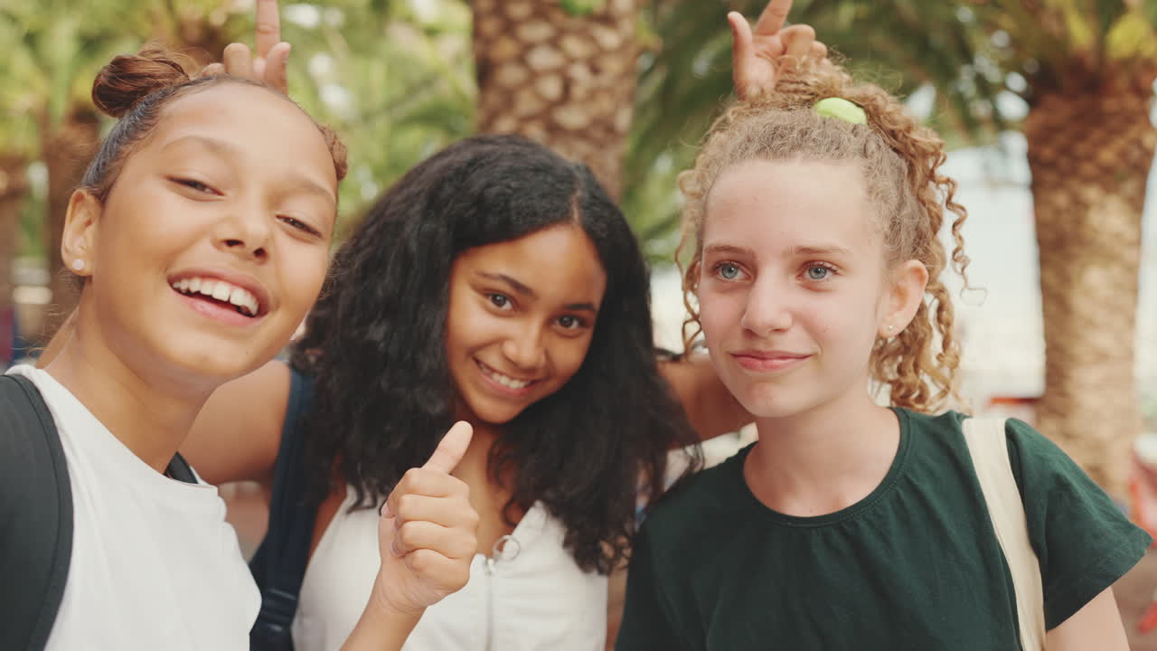 Three smiling teenage girls taking a selfie together outdoors