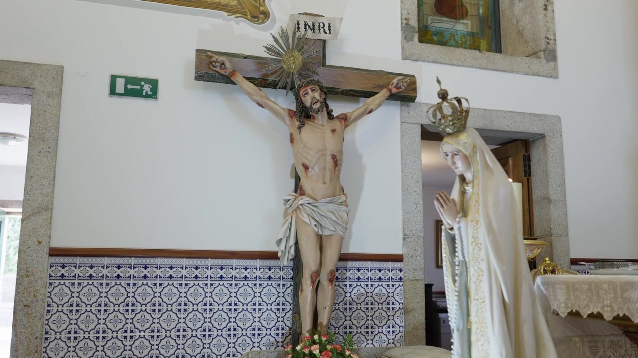 Crocifisso da chiesa con aureola d'argento accanto alla statua di Nostra Signora di Fatima sopra piastrelle azulejo.