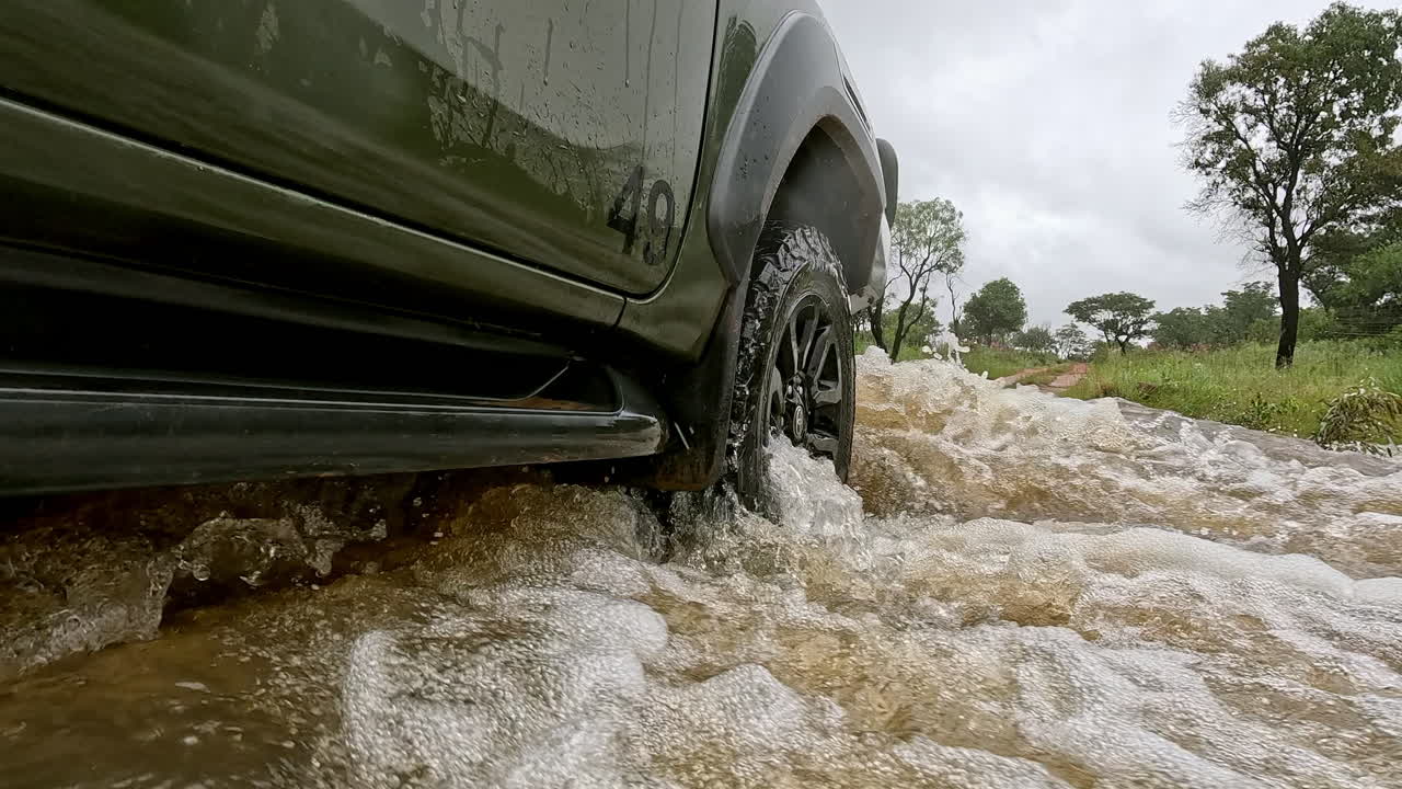 POV-sidebillede af et 4x4 køretøj, der kører over en oversvømmet lavvandsbro i et vildtreservat