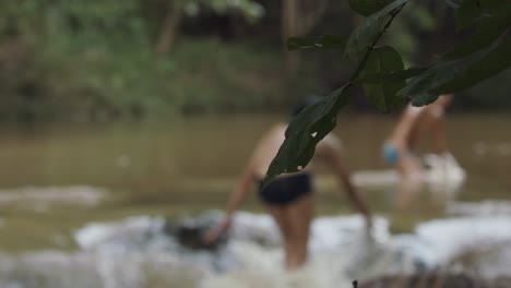 Defocused-people-wading-in-Brazil's-Rio-Vermelho-or-Red-River-with-focus-on-a-leaf-in-the-foreground-during-a-drought