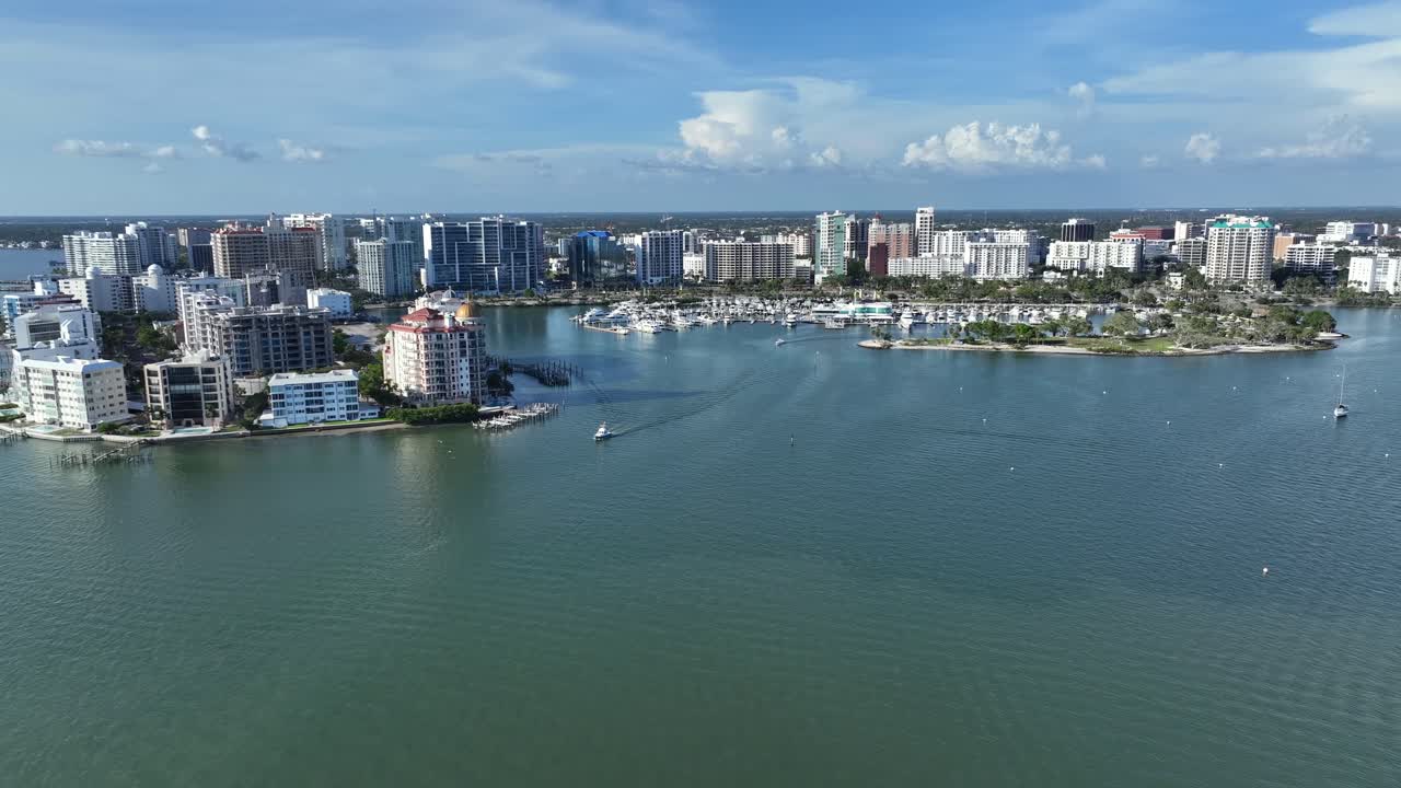 Sarasota city with cruising ship Leaving marina port. Aerial wide shot. Sunny day with blue sky. Skyline and skyscrapers along bay coast.