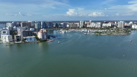 sarasota city with cruising ship leaving marina port. aerial wide shot. sunny day with blue sky. skyline and skyscrapers along bay coast.