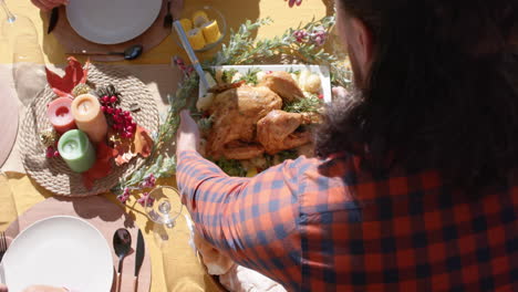 happy diverse male and female friends serving thanksgiving celebration meal in sunny garden