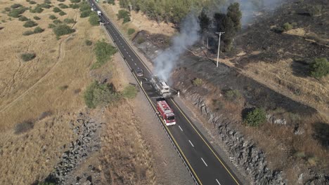 Firefighters-battling-burning-passenger-bus-on-highway,-drone-shot-footage