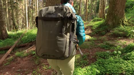 mujer caminando con una mochila de senderismo en el bosque verde de primavera