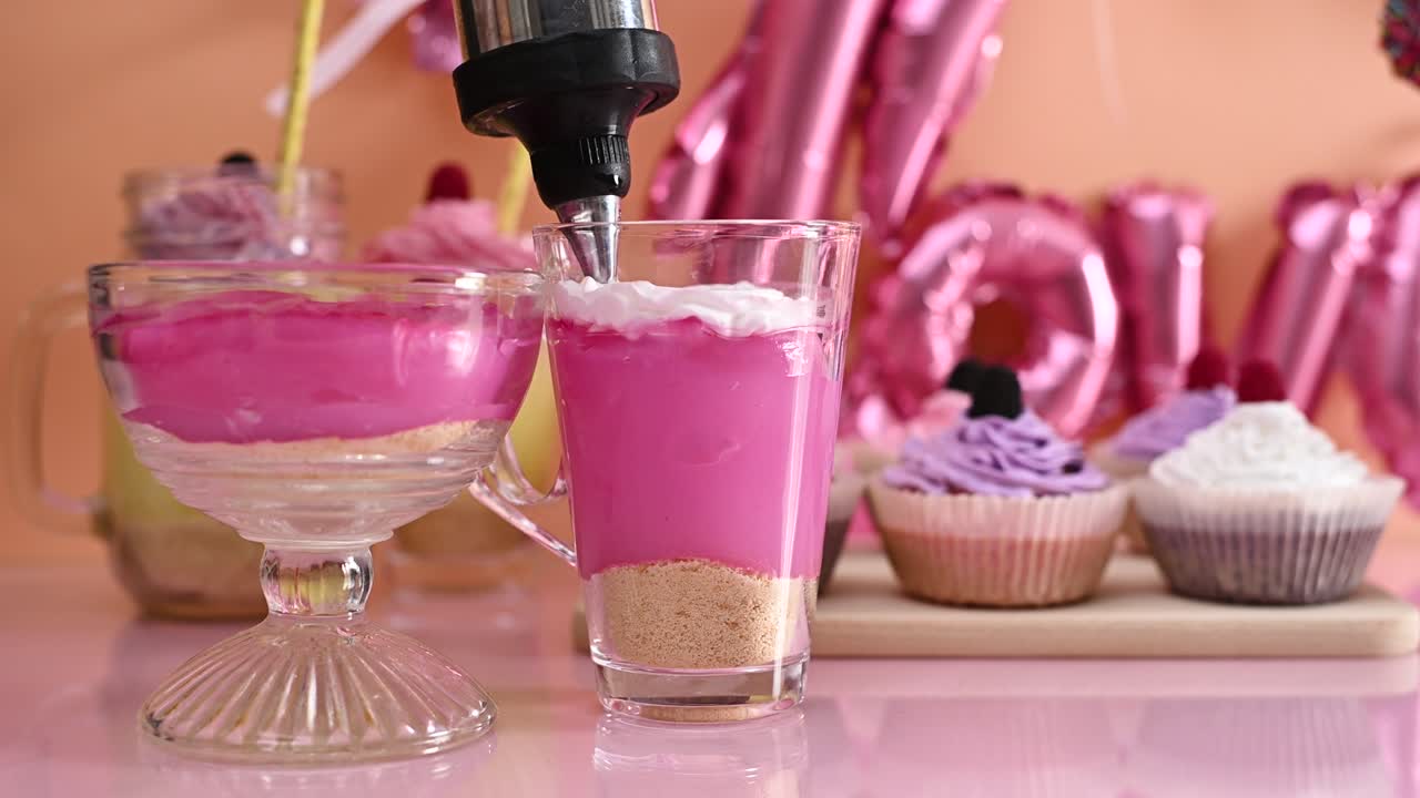 Decorando pudín de fresa en taza con crema blanca. Preparando postres dulces para fiestas. Primer plano.