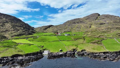 Drohnenlandschaft-Auf-Der-Abgelegenen-Halbinsel-Cods-Head,-Kleiner-Bauernhof,-Geschützt-Unter-Schroffen-Bergen-Auf-Dem-Wild-Atlantic-Way