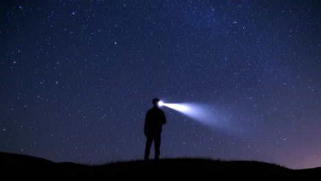 person with a flashlight under a starry night sky