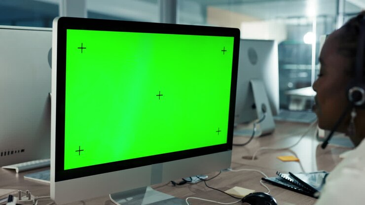 Woman in headset working at computer with green screen
