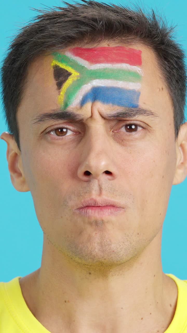 Serious man with a south african flag painted on the face