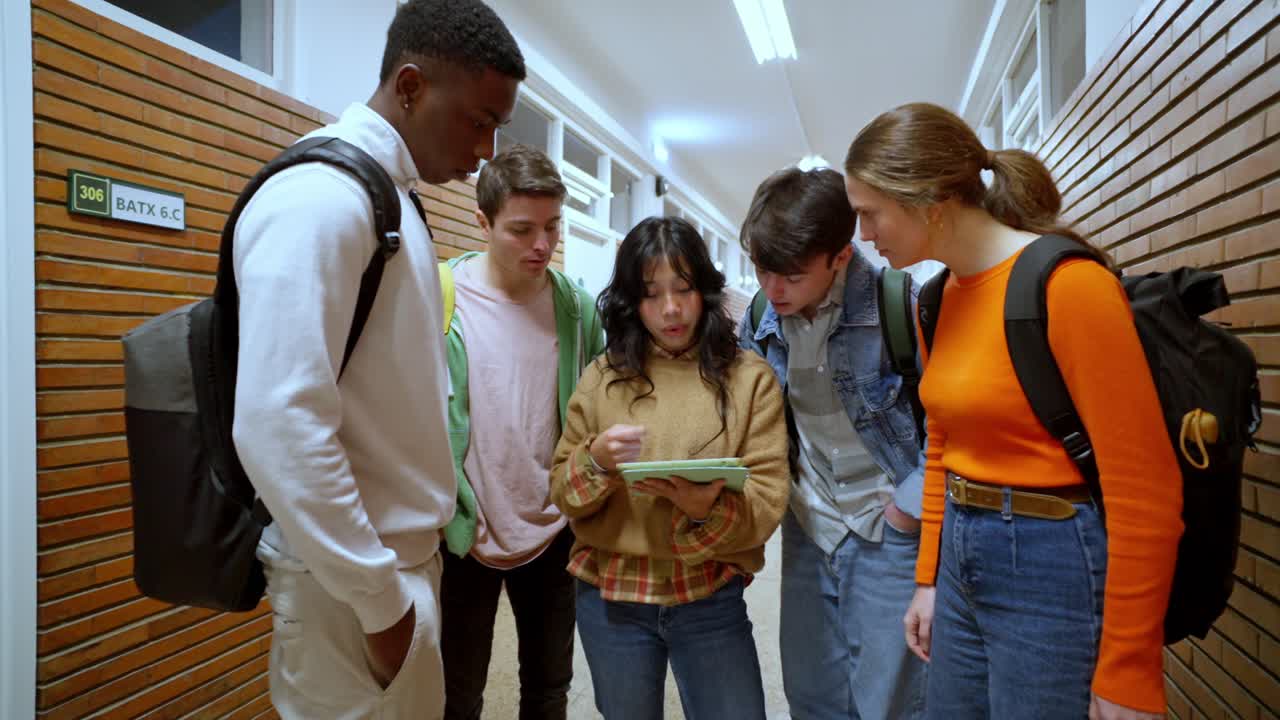 Group of students looking at a tablet in a school corridor