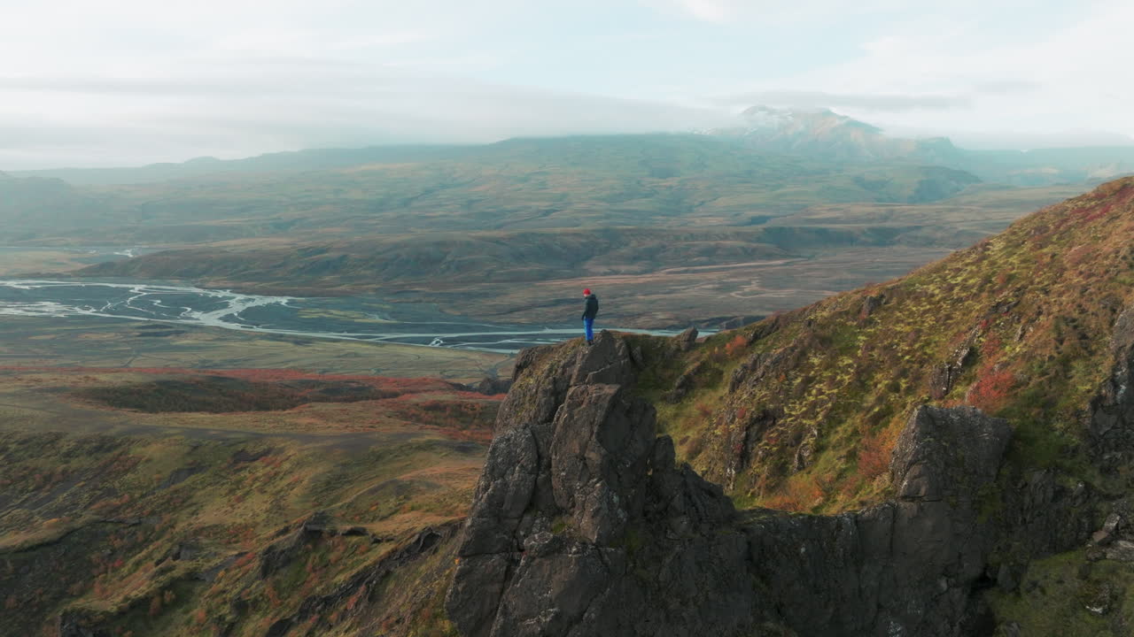 excursionista en rock spire con vistas al valle de thorsmork, islandia