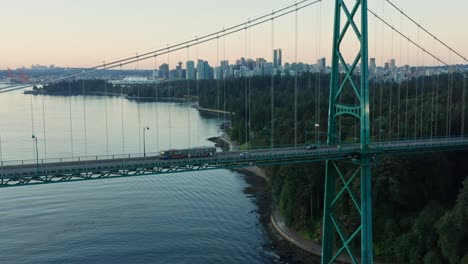 stunning drone aerial flying upwards showing lions gate bridge and vancouver cityscape during sunset - canda