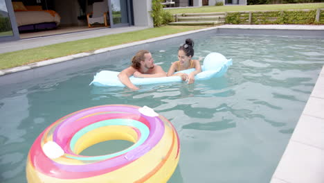 una joven pareja caucásica disfruta de un momento lúdico en una piscina, espacio de copia