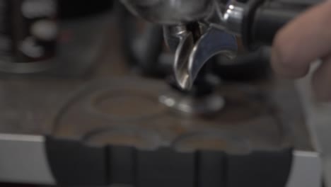 barista presses ground coffee in special barista tool