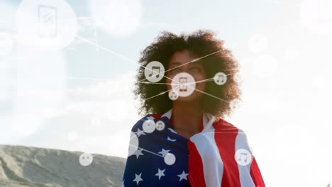 network of digital icons against african american woman wrapped in american flag smiling