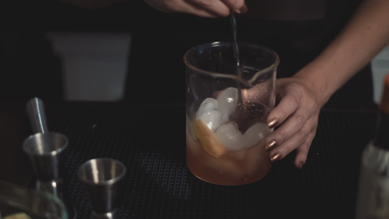 primer plano de barman mezclando cócteles artesanales en hielo con una cuchara de barra alta