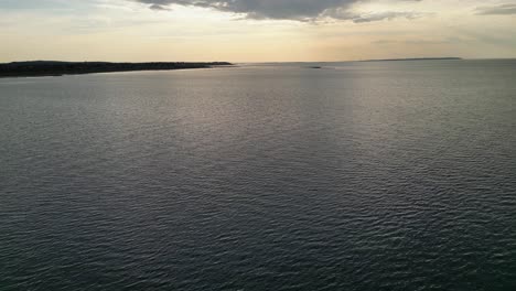 Drone-shot-revealing-a-boat-in-the-sea-against-the-sunset-in-the-late-afternoon