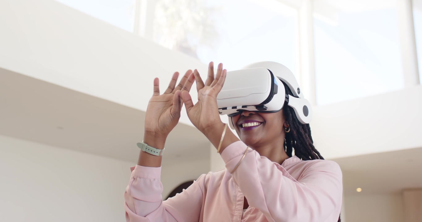 Adulto afroamericano che indossa un visore VR bianco, toccando oggetti virtuali ed esplorando la casa con una fascia color menta.