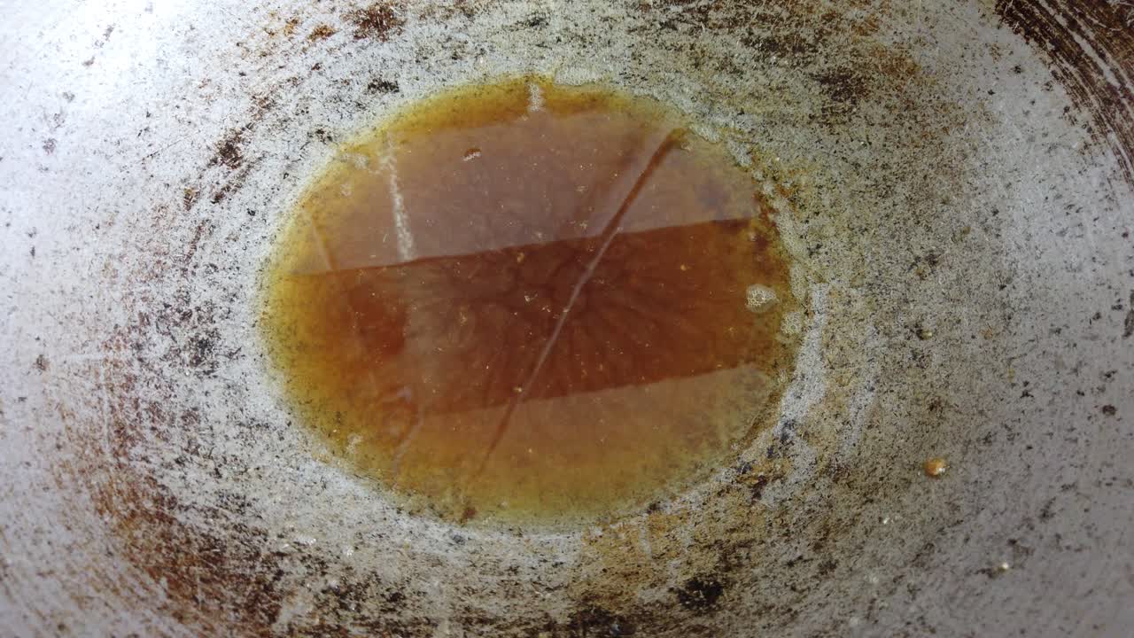a chef is frying anchovies in the hot palm oil and metal pan