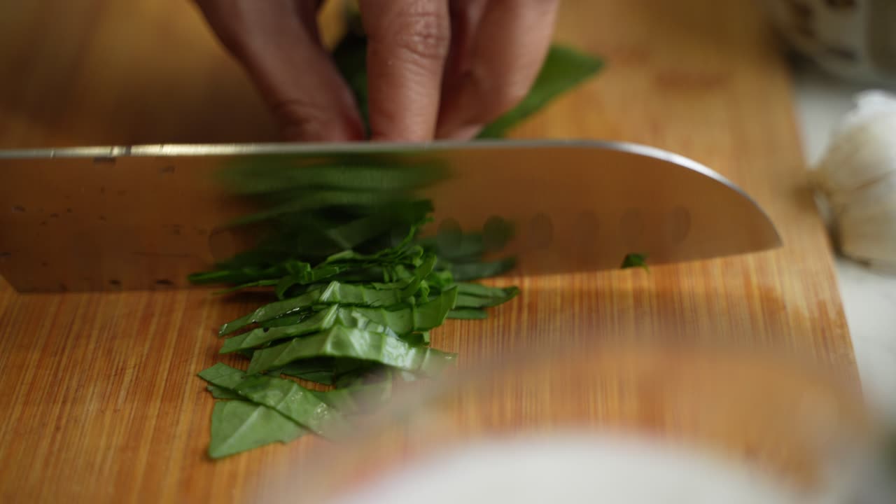 Chef cutting leaves to be used at recipe using knife.