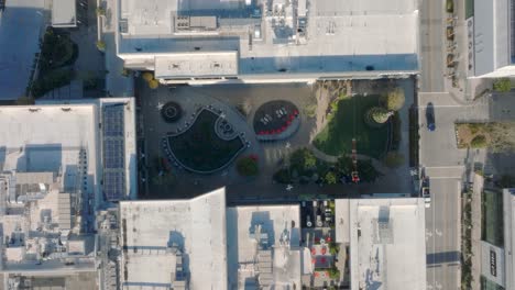 rising drone shot of the outdoor green space and rooftops in the hillsdale shopping center