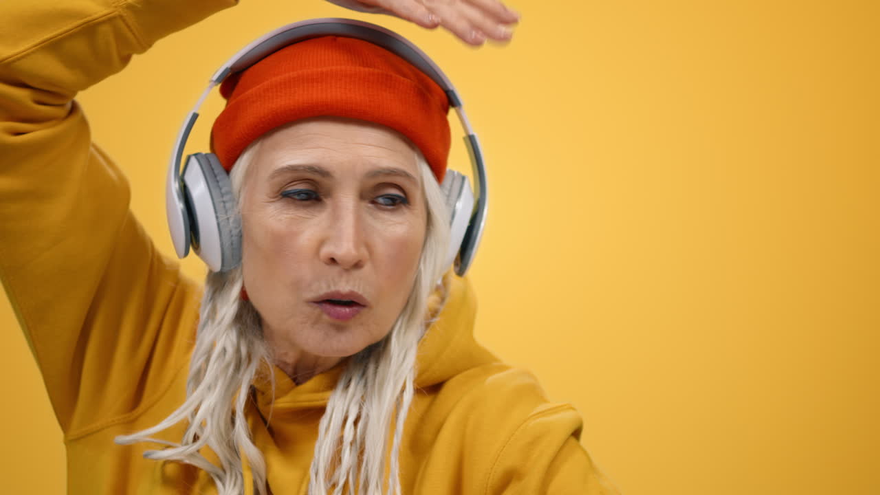 una mujer mayor sonriente moviendo las manos en el estudio. una mujer alegre divirtiéndose en el interior.