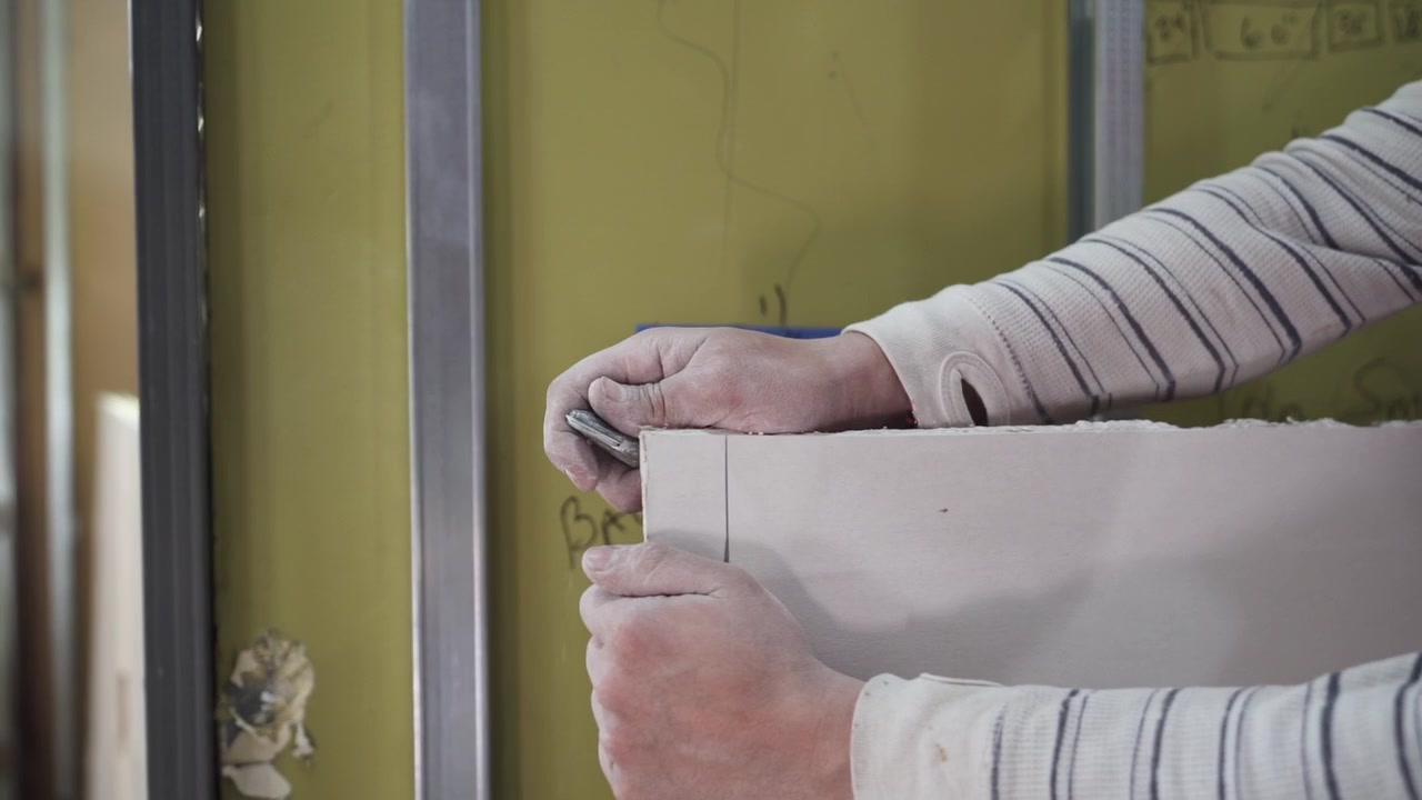 Tracking shot of contractor trimming drywall for restaurant renovation in slow motion.