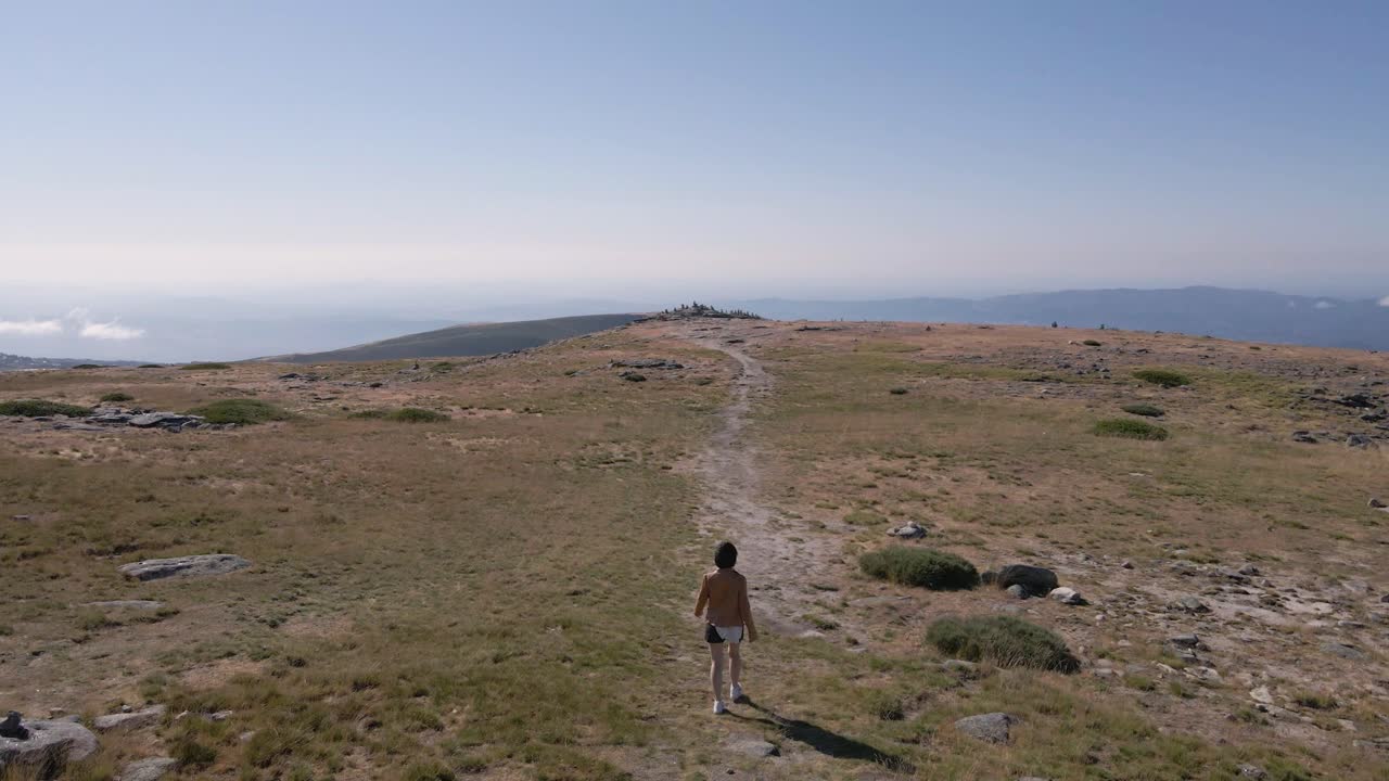 Donna di spalle che cammina verso il punto panoramico alla Torre di Serra da Estrela, Portogallo
