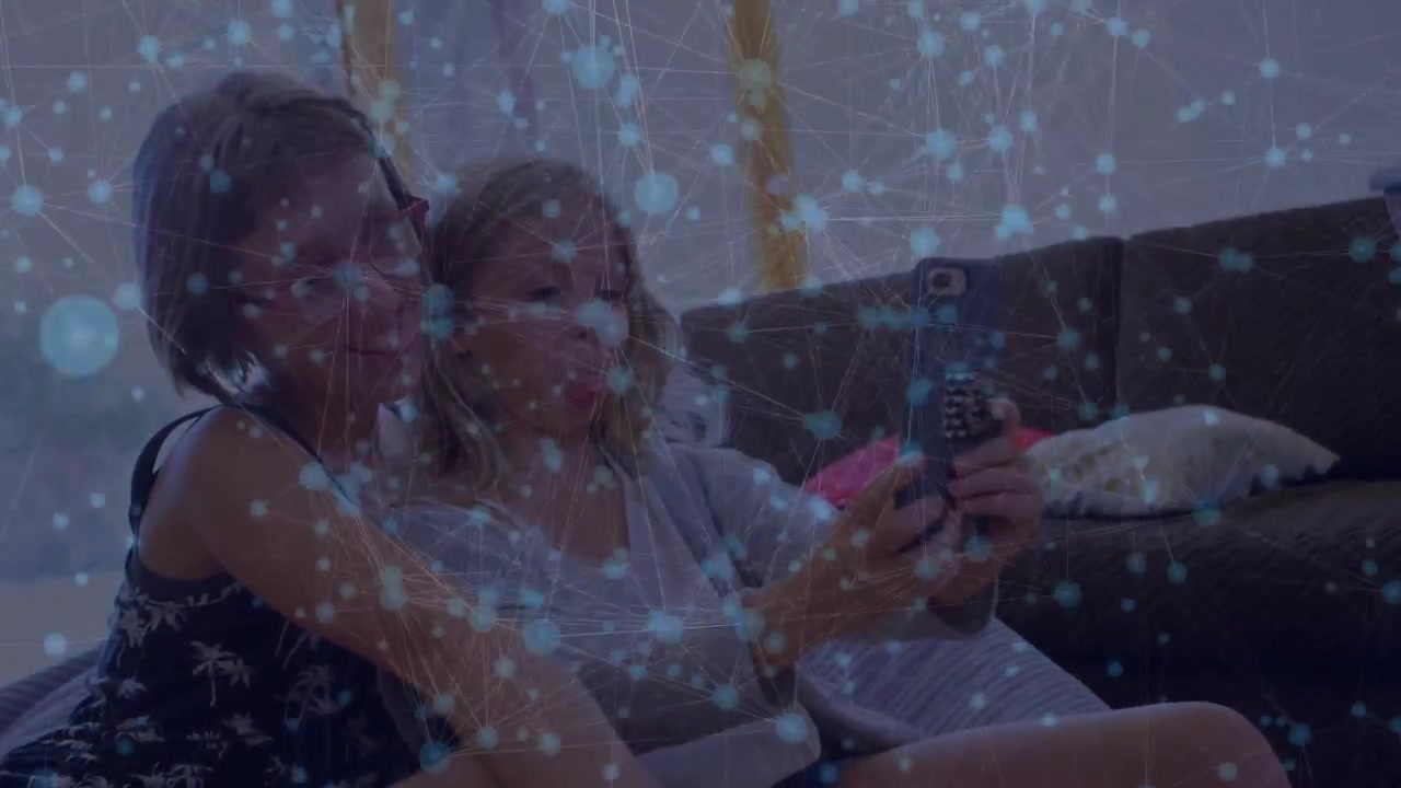 Sorelle che si sistemano sul divano e prendono lo smartphone, inquadrando un selfie e posando per i social media.