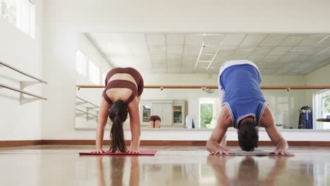 focused caucasian male instructor and female student practicing yoga in gym, slow motion