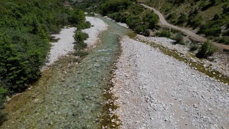 Volando-Sobre-El-Arroyo-De-La-Montaña-Con-Agua-Fría-Y-Limpia-Rodeada-De-árboles-Verdes,-Rama-Del-Río-Vjosa-En-Albania