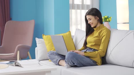 Young-woman-writing-and-working-as-a-freelancer-on-laptop-while-sitting-in-living-room.