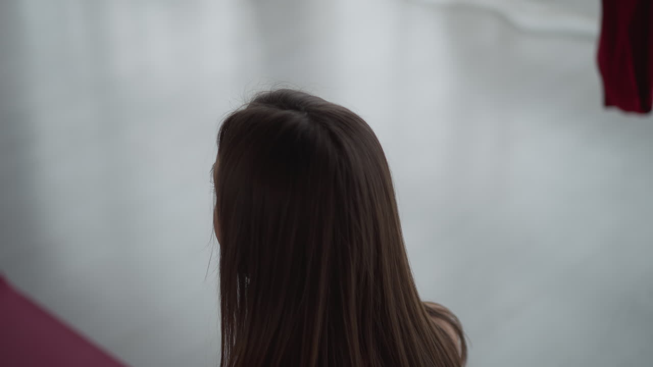 High angle of zen enthusiast in sportswear practicing mindful yoga session on red mat with hands on chest and stomach in serene indoor studio with soft ambient light and hanging silk fabrics