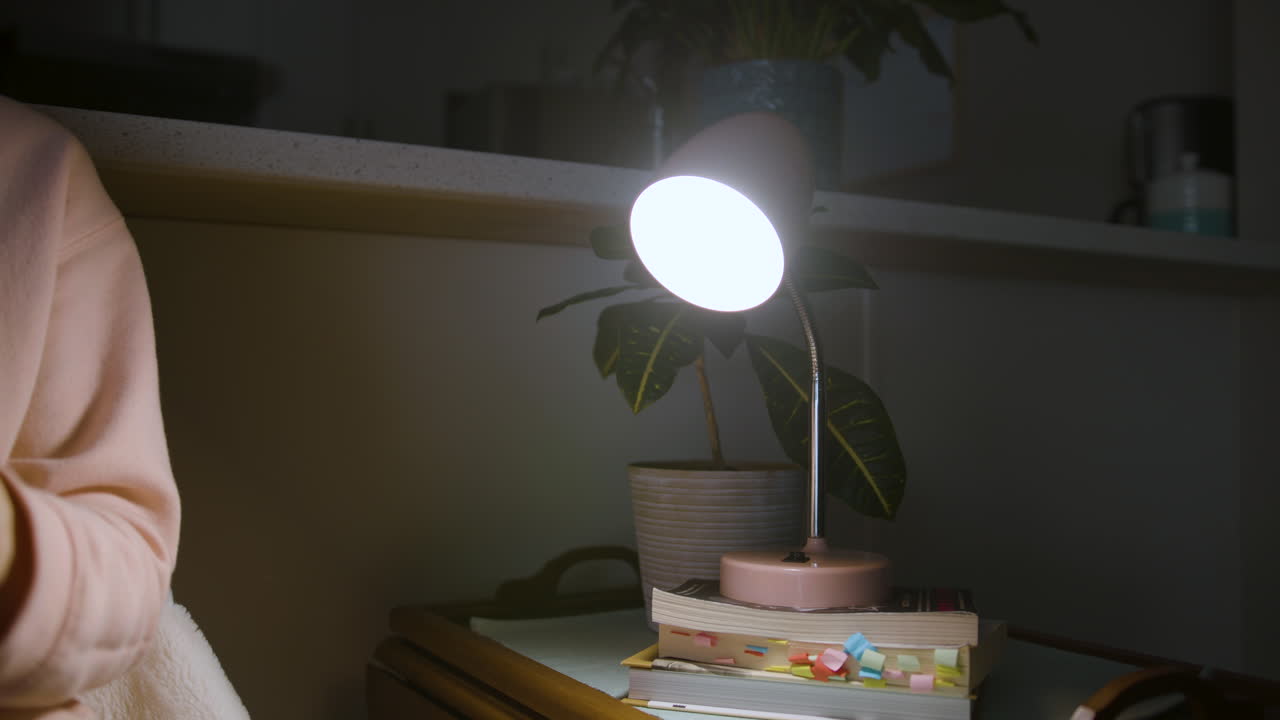 A small lamp flickers with possible power outage as a woman sits next to it