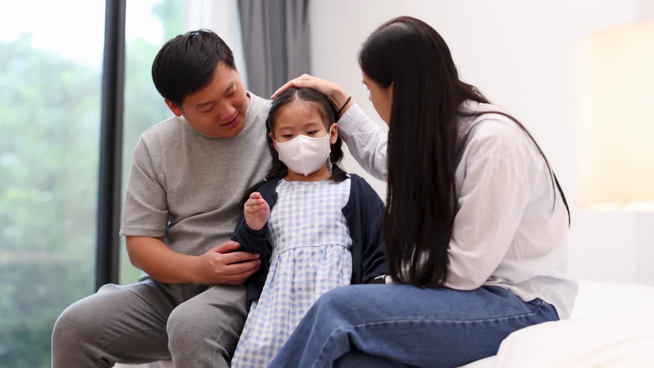 Mother and father care for ill daughter in bright bedroom, checking fever and offering comfort