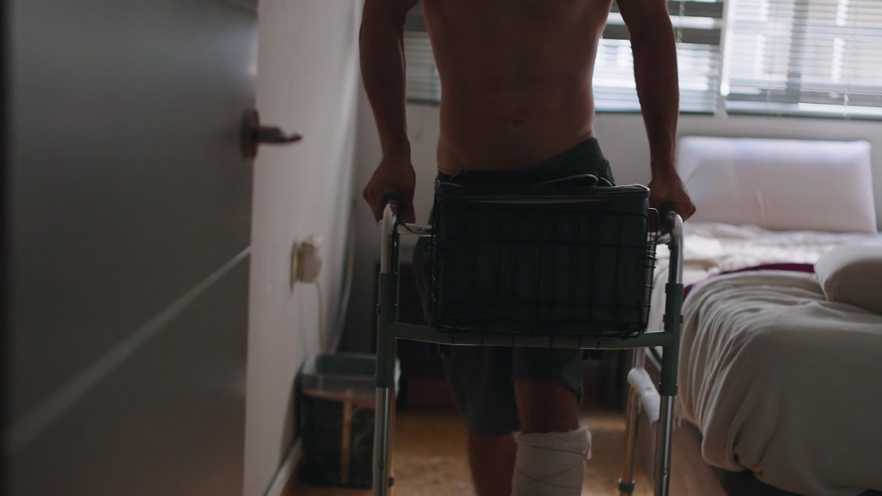 Homem com lesão na perna usando andador no quarto