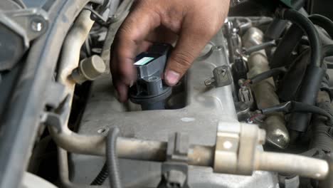 una mano usando un par de alicates y tijeras separando un tubo de goma del bloque del motor en un taller de reparación en bangkok, tailandia