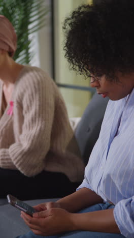 vertical video of upset young woman patient wearing headscarf receiving chemotherapy treatment for breast cancer being comforted by female patient 1