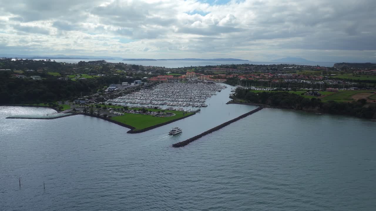 Vista aerea di un traghetto passeggeri che entra nella marina di Gulf Harbour, circondato da barche ormeggiate e case sul lungomare.