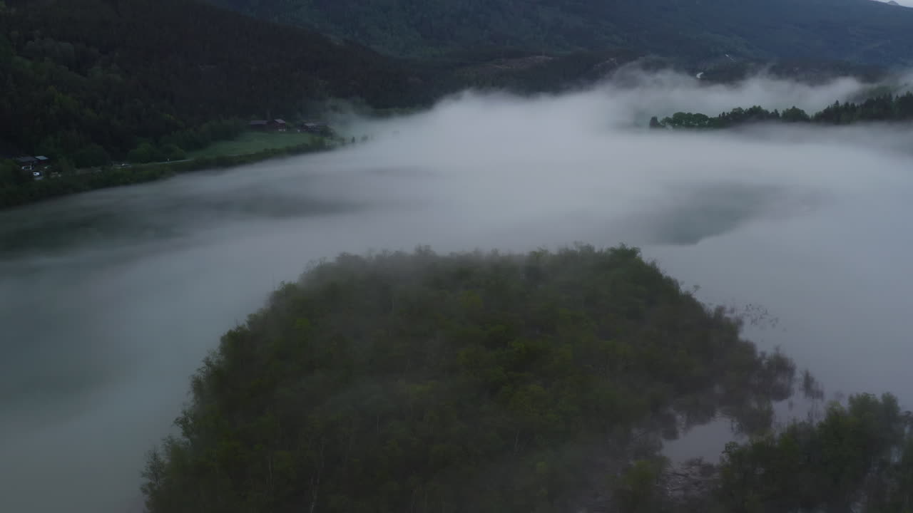 Flight over a foggy river. The mist is hanging low over the landscape creating a dark mystical mood over the whole scene