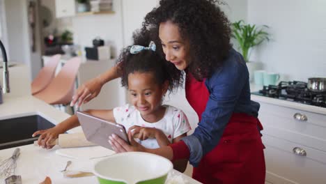 Glückliche-Afroamerikanische-Mutter-Und-Tochter,-Die-Zusammen-Ein-Tablet-Benutzen-Und-Backen